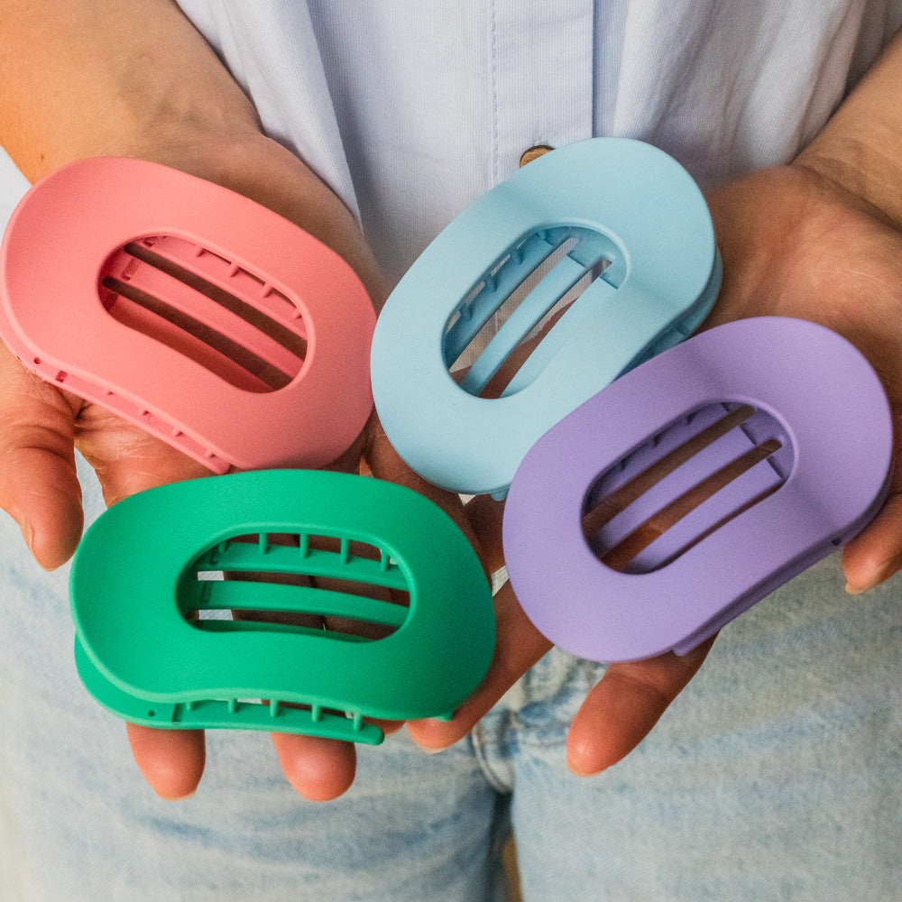 Set van kleurrijke haarklemmen in roze blauw paars en groen vastgehouden in hand trendy haaraccessoires