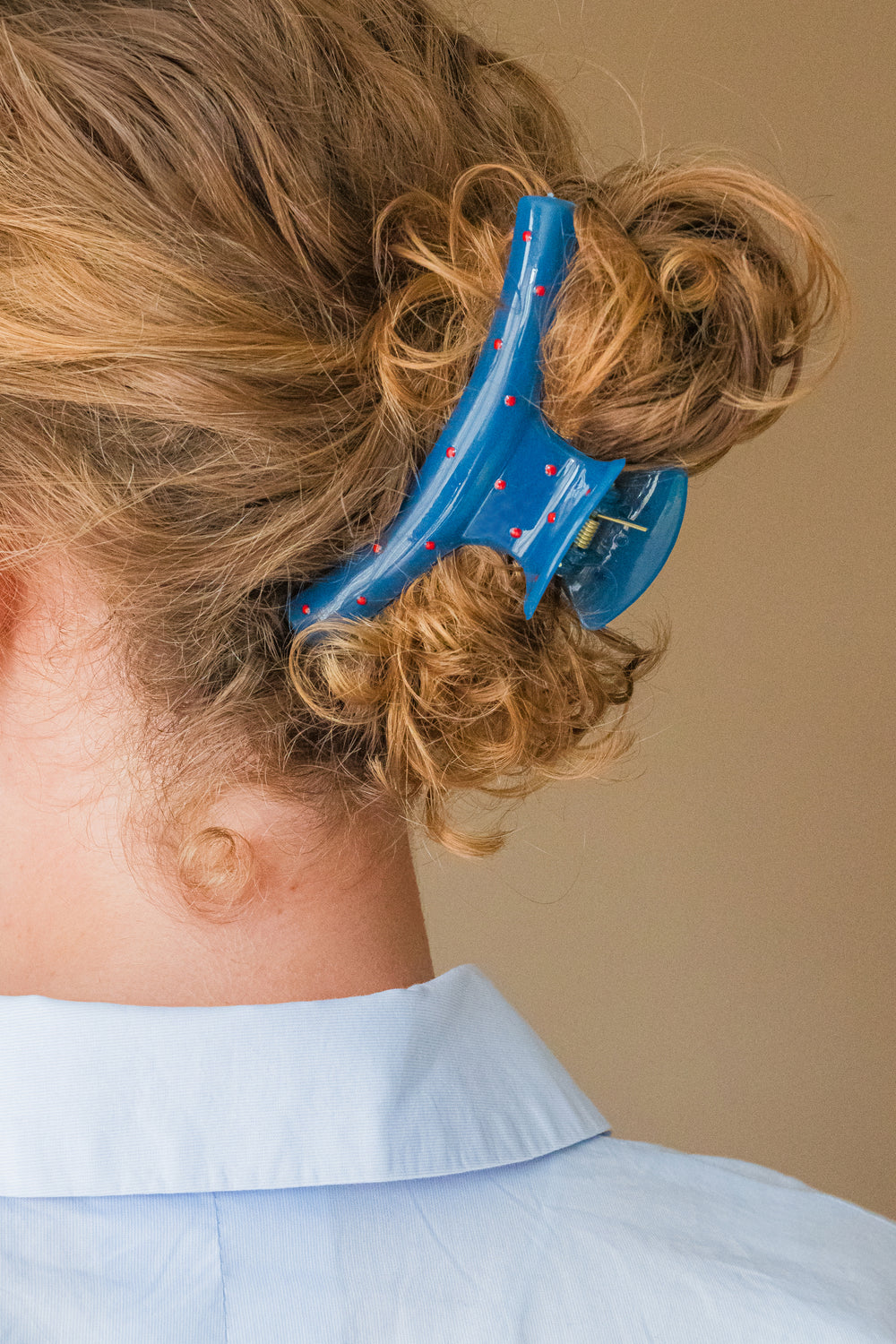 Blauwe haarklem met rode stippen in licht krullend haar dames haaraccessoire